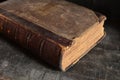 Old leather bound book laying on a dusty wooden bookshelf Royalty Free Stock Photo