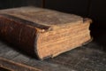 Old leather bound book laying on a dusty wooden bookshelf Royalty Free Stock Photo