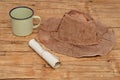 An old leather hat with a paper scroll and tin mug Royalty Free Stock Photo