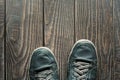 Old leather sneakers stepping on wooden boards. Royalty Free Stock Photo