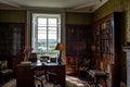 Old library with a desk and vintage lamp in a historical room with a bright window