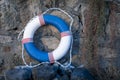 Old lifebuoy next to stone wall by the sea. Marine retro background