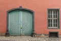 Old light green wooden door in ochre concrete wall with window. Royalty Free Stock Photo