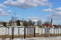 Old light grey garages in the line, metal fence and church at the back, winter view Royalty Free Stock Photo