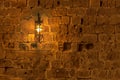 Old light lamp at night hanging on a medieval street fortress wall Royalty Free Stock Photo
