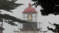 Old lighthouse fresnel lens glowing, foggy rainy weather. Illuminated beacon USA