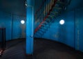 Old lighthouse on the inside. Red iron spiral stairs, round window and blue wall Royalty Free Stock Photo