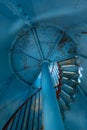 Old lighthouse on the inside. Red iron spiral stairs, round window and blue wall. Royalty Free Stock Photo