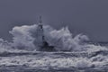 Old lighthouse in the middle of great stormy waves.Crashing big sea wave against rocks splash and spray .Huge stormy sea wave Royalty Free Stock Photo