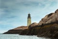 Old Lighthouse Tower on Rocky Maine Island as Sun Breaks Through Storm Clouds