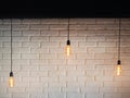 Old lighting electric bulb, Retro lamp on a background of a white brick wall. Edison bulb hanging on a wire. Three bulbs on a wire Royalty Free Stock Photo