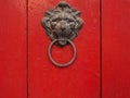 Old lion door knocker on bright red door.