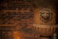 Old lion flower vase in front of a brick wall