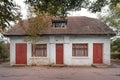 Old little shabby one-story white brick house with red doors and windows in the woods Royalty Free Stock Photo