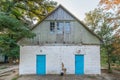 Old little shabby one-story white brick house with two blue doors in the woods Royalty Free Stock Photo