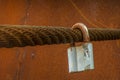 The old lock hangs on a thick rusty iron cable