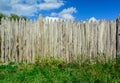 An old log fence and a blue sky with clouds. Security and fencing. Protection against thieves. Royalty Free Stock Photo