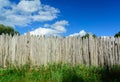 An old log fence and a blue sky with clouds. Security and fencing. Protection against thieves. Royalty Free Stock Photo