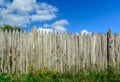 An old log fence and a blue sky with clouds. Security and fencing. Protection against thieves. Royalty Free Stock Photo