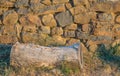 An old log next to an old stone wall