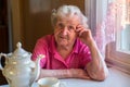 Old lone lady drinking tea sitting in the kitchen. Royalty Free Stock Photo