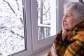 Old lonely woman sitting near the window in his house Royalty Free Stock Photo