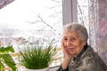 Old lonely woman sitting near the window in his house Royalty Free Stock Photo