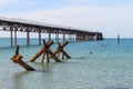 The old long rusty pier going into the sea. There is a man standing on the pier. In the foreground of the water sticking Royalty Free Stock Photo