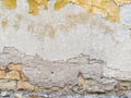 Old looking facade wall with pieces of old yellow facade left of a color that used to be with rough texture of bricks showing and
