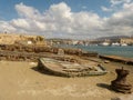 The old lounging boat lies on the sand against the background of the promenade of Chania