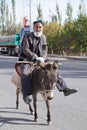 Old lovely Uygur man riding a small cute dongkey