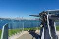 An old machine gun on display by Naval base in Devonport with Auckland city skyline across harbor