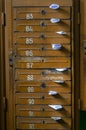 Old mailboxes in the entrance hall of a residential house filled with white paper flyers. Mass mailing concept