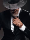 An old male actor playing an English spy role, hiding behind fedora hat.