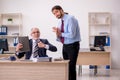 Old male boss and young employee working in the office Royalty Free Stock Photo