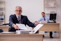 Old male boss and young employee working in the office Royalty Free Stock Photo