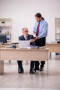 Old male boss and young employee working in the office