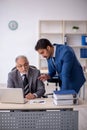 Old male boss and young male employee working in the office Royalty Free Stock Photo