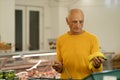 Old male buying food at supermarket, choosing bananas in fruit department. Grocery store shopping. Royalty Free Stock Photo