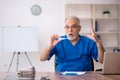 Old male doctor holding thermometer in the clinic Royalty Free Stock Photo