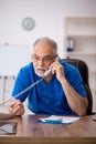 Old male doctor holding thermometer in the clinic Royalty Free Stock Photo