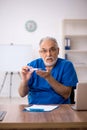 Old male doctor holding thermometer in the clinic Royalty Free Stock Photo