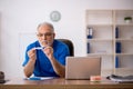 Old male doctor holding thermometer in the clinic Royalty Free Stock Photo