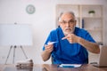 Old male doctor holding thermometer in the clinic Royalty Free Stock Photo