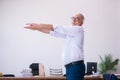 Old businessman employee doing sport exercises in the office Royalty Free Stock Photo