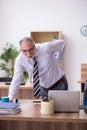 Old male employee suffering from radiculitis at workplace