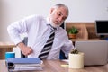 Old male employee suffering from radiculitis at workplace Royalty Free Stock Photo