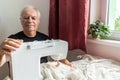 Old male man senior sit next at table at home work, sewing machine enjoy Royalty Free Stock Photo