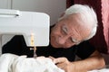 Old male man senior sit next at table at home work, sewing machine enjoy Royalty Free Stock Photo