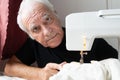 Old male man senior sit next at table at home work, sewing machine enjoy Royalty Free Stock Photo